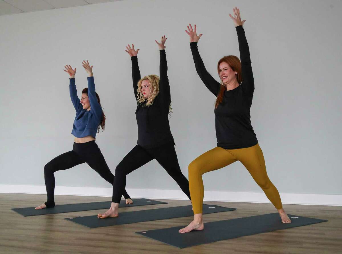 Amanda Hale, owner of Yoga Tres in the studio, right, demonstrates a Warrior One pose with Heather Heft, center and Stacie Zollars, far left, Thursday, Jan. 20, 2022 in Bellaire. Story is about how yoga can help with blood pressure.