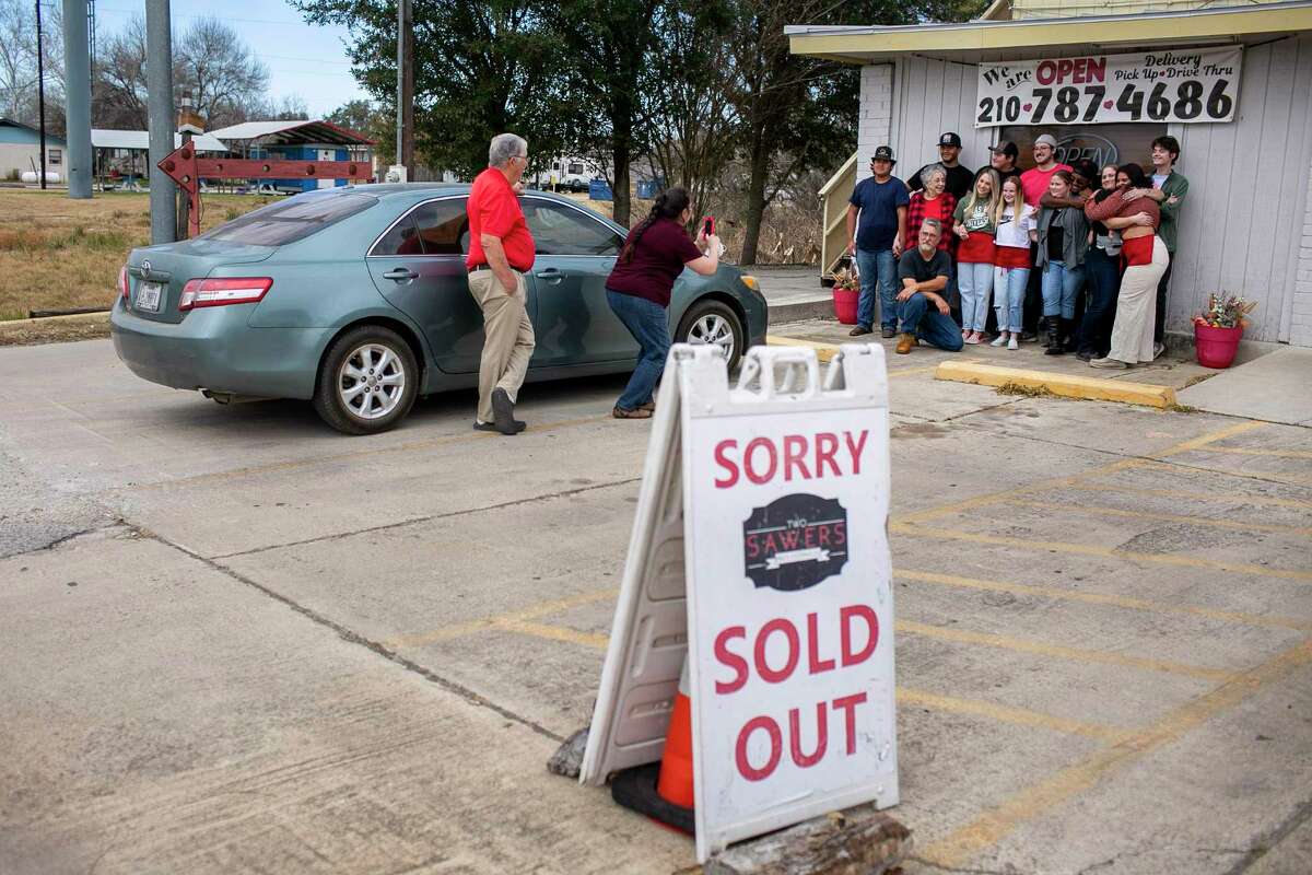 The Two Sawers BBQ staff pose together outside the business after selling out on the last day of business in Floresville on Jan. 22.