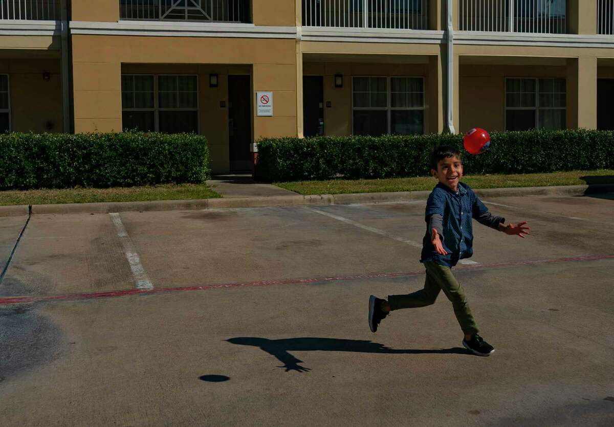 Abdul Wajid Hekmat’s 8-year-old son chases a ball through the parking lot of the extended stay motel where the family of six has been living for the past two weeks, Friday, Jan. 28, 2022, in Fort Bend County.