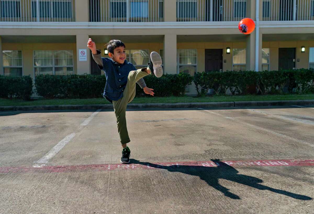Abdul Wajid Hekmat’s 8-year-old son kicks a ball through the parking lot of the extended stay motel where the family of six has been living for the past two weeks, Friday, Jan. 28, 2022, in Fort Bend County.