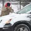 A man removes ice from his windshield wipers on West Street in Danbury, Saturday morning, January 29, 2022, during a snowstorm.