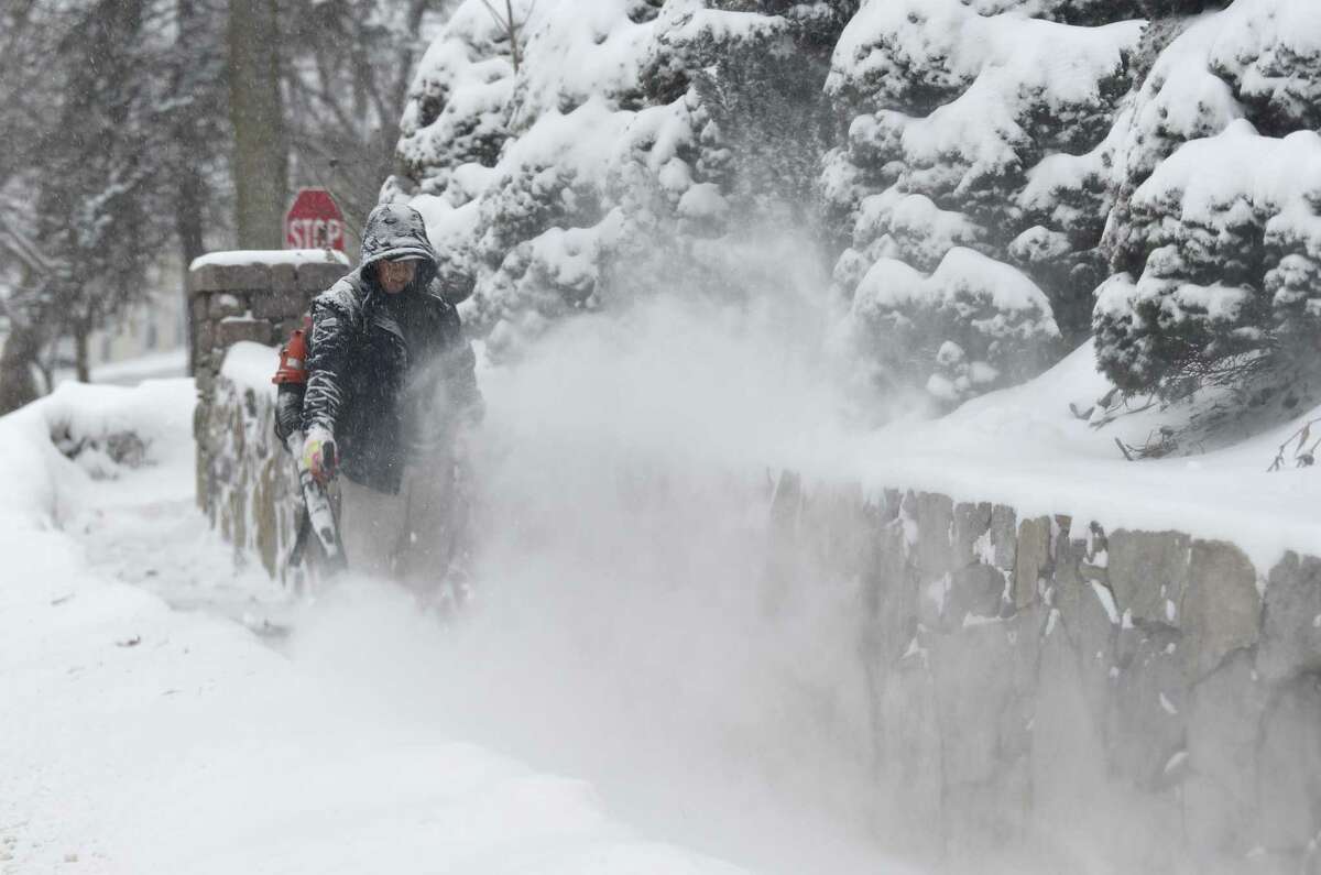 Saturday morning a man uses a blower to clear the snow on a sidewalk on West Street in Danbury during the day’s snowstorm, January 29, 2022.