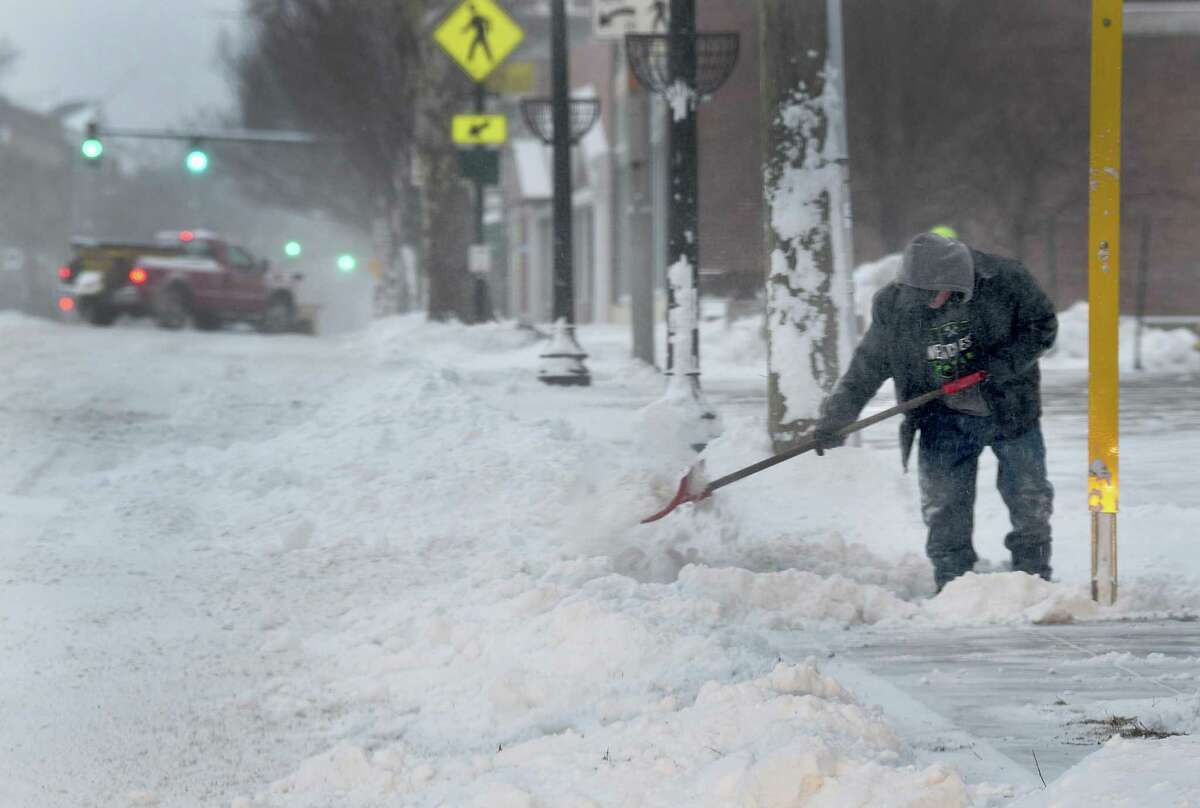 A man shovels snow from the sidewalk in front of St. Peter Church in Danbury Saturday morning, January 29, 2021.