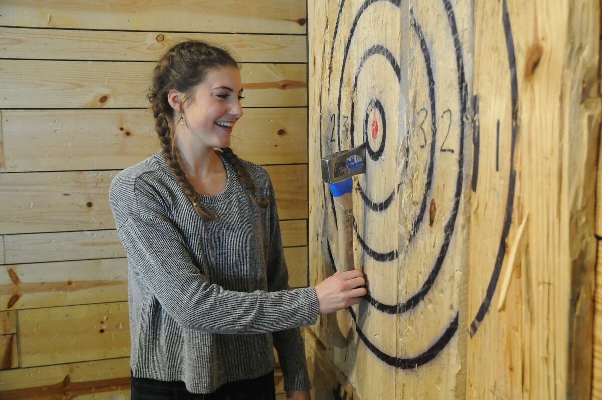 Novice thrower Monica Wendle, 18, of Godfrey is pleased with her newfound skill as she removes an axe from the target at Riverband Axe Throwing on Saturday.  