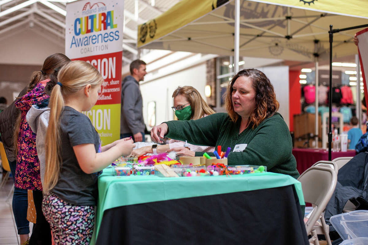 Emily Migut, volunteer with the Midland Cultural Awareness Coalition, helps kids decorate paper people during the Kids' Day at the Midland Mall event on Jan. 29, 2022.