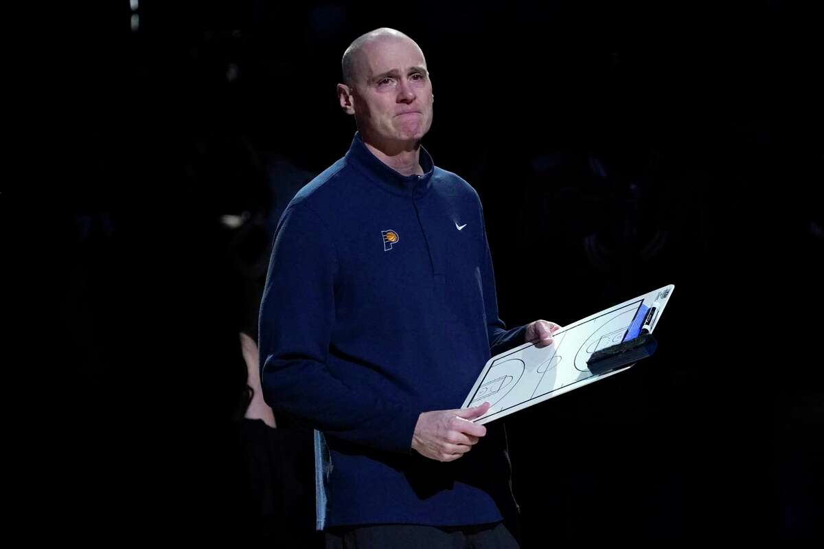 Indiana Pacers head coach Rick Carlisle fights back tears as he watches a video tribute honoring Carlisle's time in Dallas that was played on the large in-house video screen before the first half of an NBA basketball game against the Dallas Mavericks in Dallas, Saturday, Jan. 29, 2022. (AP Photo/Tony Gutierrez)