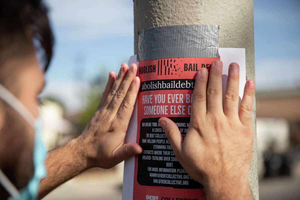 Manuel Galindo puts up posters at Watts Towers of Simon Rodia State Historic Park in Los Angeles in September. The posters offer solutions to people with bail debt.
