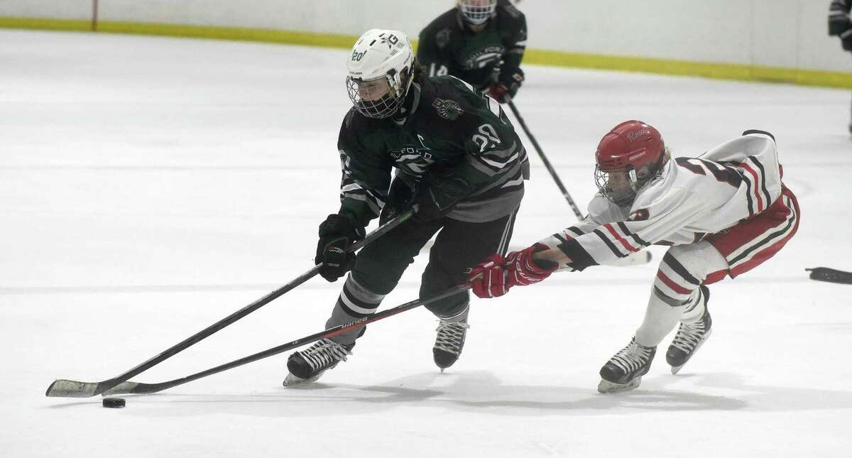 Guilford's Maddie Epke (20) skates into the offensive zone while New Canaan's Lexie Tully (23) defends during a girls ice hockey game at the Darien Ice House on Sunday, Jan. 30, 2022.
