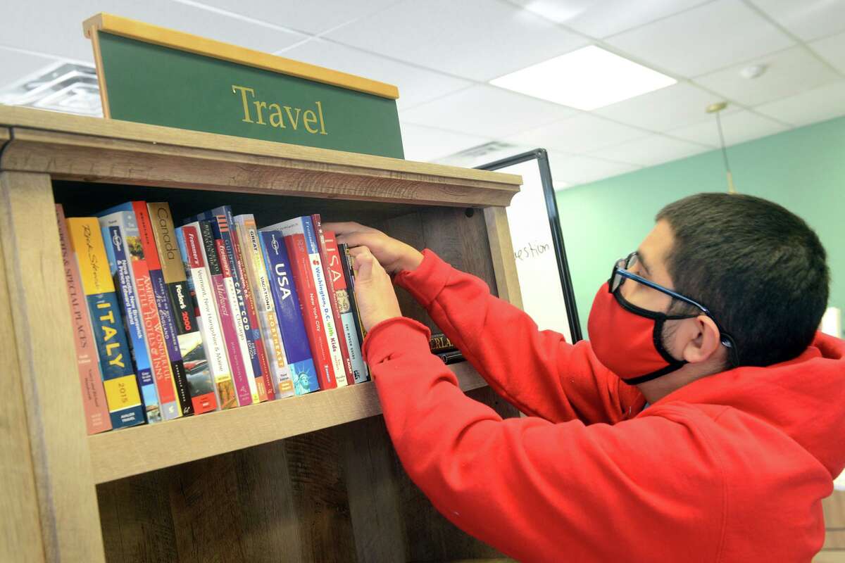 Luis Contreras places books on the shelves at The Next Chapter, Books & More!, in Trumbull, Conn. Jan. 26, 2022.