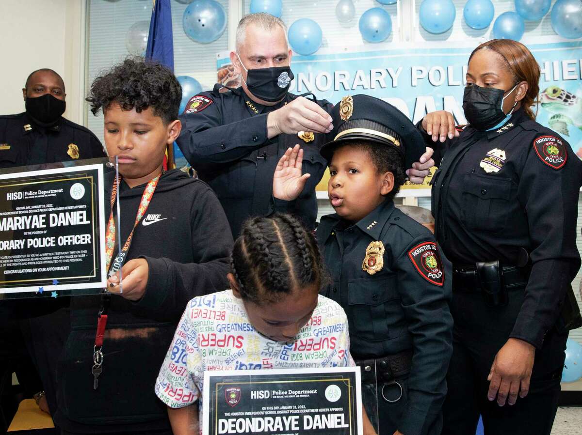 Houston ISD Police Chief Pedro Lopez, Jr. puts the hat on 10-year-old Devarjaye “DJ” Daniel after he has sworn in as an honorary police chief during a ceremony Monday, Jan. 31, 2022, at HISD Police Headquarters in Houston. DJ has terminal brain and spinal cancer and wants to be sworn into 100 law enforcement agencies to raise awareness to childhood cancer. His brothers, Demariyae Daniel, left, 11, and Deondraye Daniel, 7, were looking at their honorary police officer certificates.