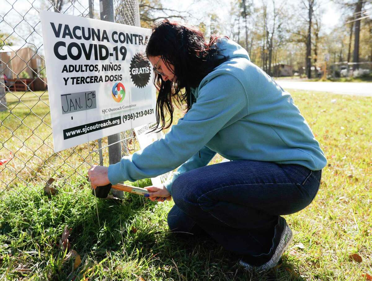 Makayla Currie places a sign in front of the Deerwood Community Center as she and other volunteers with the Texas Familias Council open a COVID-19 and flu vaccination clinic, Saturday, Jan. 15, 2022, in Conroe. The center was recently renovated after having freeze damage in February.