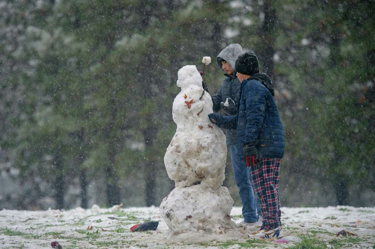 Brothers Angel (left) and Marcos Santana of Sacramento build a snowman in Colfax the day after Christmas. Precipitation levels have dropped significantly since last month.