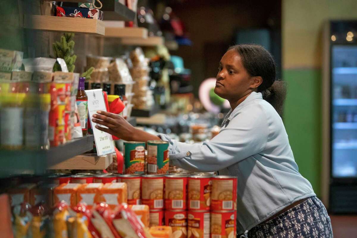 Danielle Mitchell browses the selection of products on a shelf at the District Market Green Grocer, Saturday, Jan. 29, 2022, in Houston. Robert Thomas opened the business after his nightclub in the same space had to close during the pandemic. Now the store supports other small, Black-owned businesses by selling an array of products from fresh produce to baked goods to local, organic washing detergent.