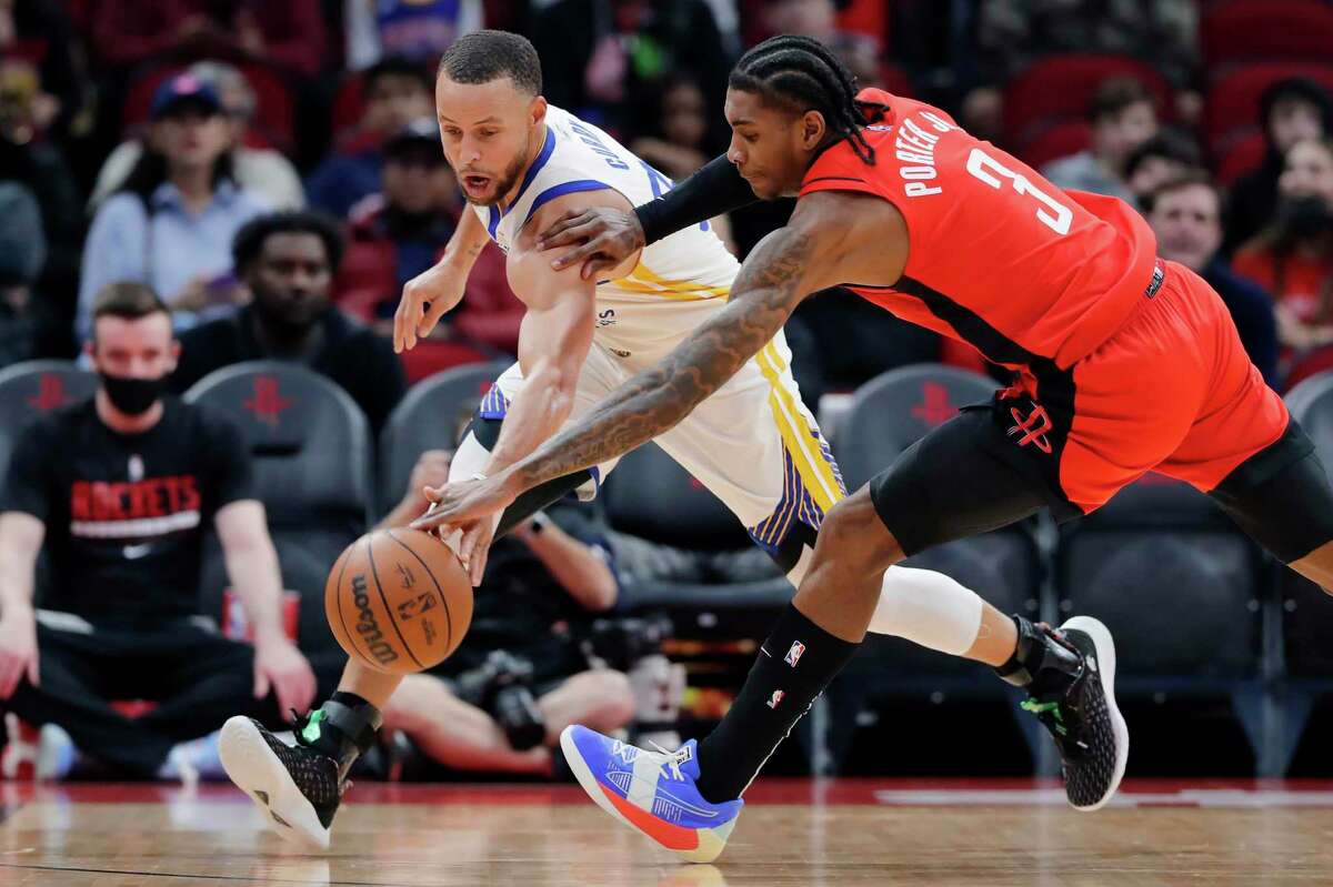 Golden State Warriors guard Stephen Curry, left, and Houston Rockets guard Kevin Porter Jr. (3) battle for the ball during the first half of an NBA basketball game Monday, Jan. 31, 2022, in Houston. (AP Photo/Michael Wyke)