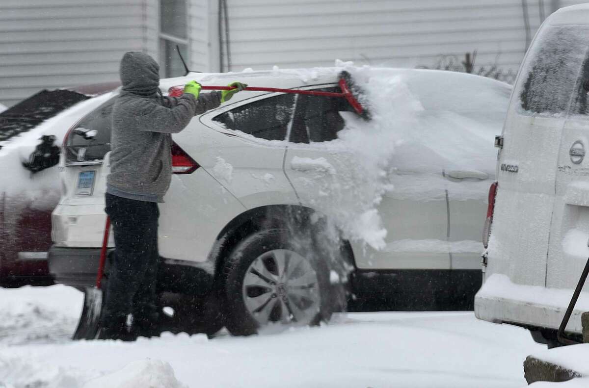 A resident sweeps snow from a car on East Liberty Street in Danbury, Saturday morning, January 29, 2022.