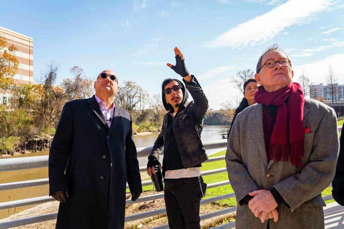 Richard Molina, center, talks about the mural that will take up a wall along the Buffalo Bayou with Gilbert Andrew Garcia, left, and architect William T. Cannady as they tour the site of the planned mural and memorial to José “Joe” Campos Torres, Friday, Jan. 28, 2022, in Houston. Campos Torres was murdered by Houston police and dumped in Buffalo Bayou in 1977 near the spot of the planned memorial.