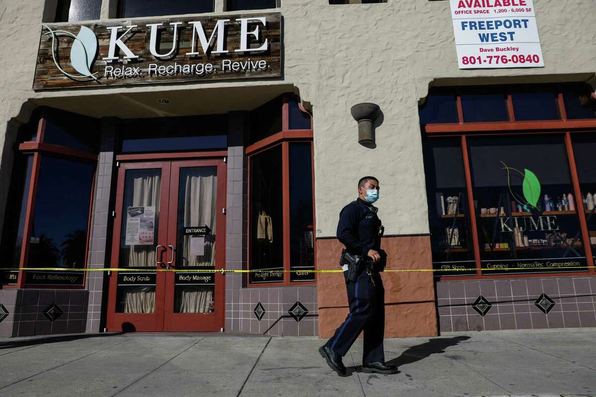 A police officer walks outside the scene of a shooting at Kume spa on Tuesday, Feb. 1, 2022 in Oakland, Calif. Two people, employees of the spa, were in critical condition following the shooting, according to police.