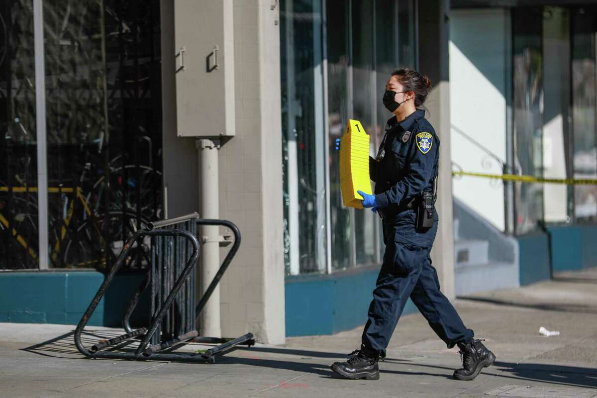 A police officer carries crime scene markers at the site of a shooting at Kume Spa on Tuesday, Feb. 1, 2022 in Oakland, Calif. Two people, employees of the spa, were in critical condition following the shooting, according to police.