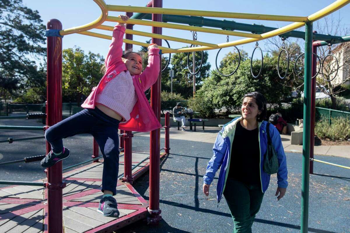 Dr. Rita Hamad watches as her 5-year-old daughter plays on the playground at Parkside Square in San Francisco.