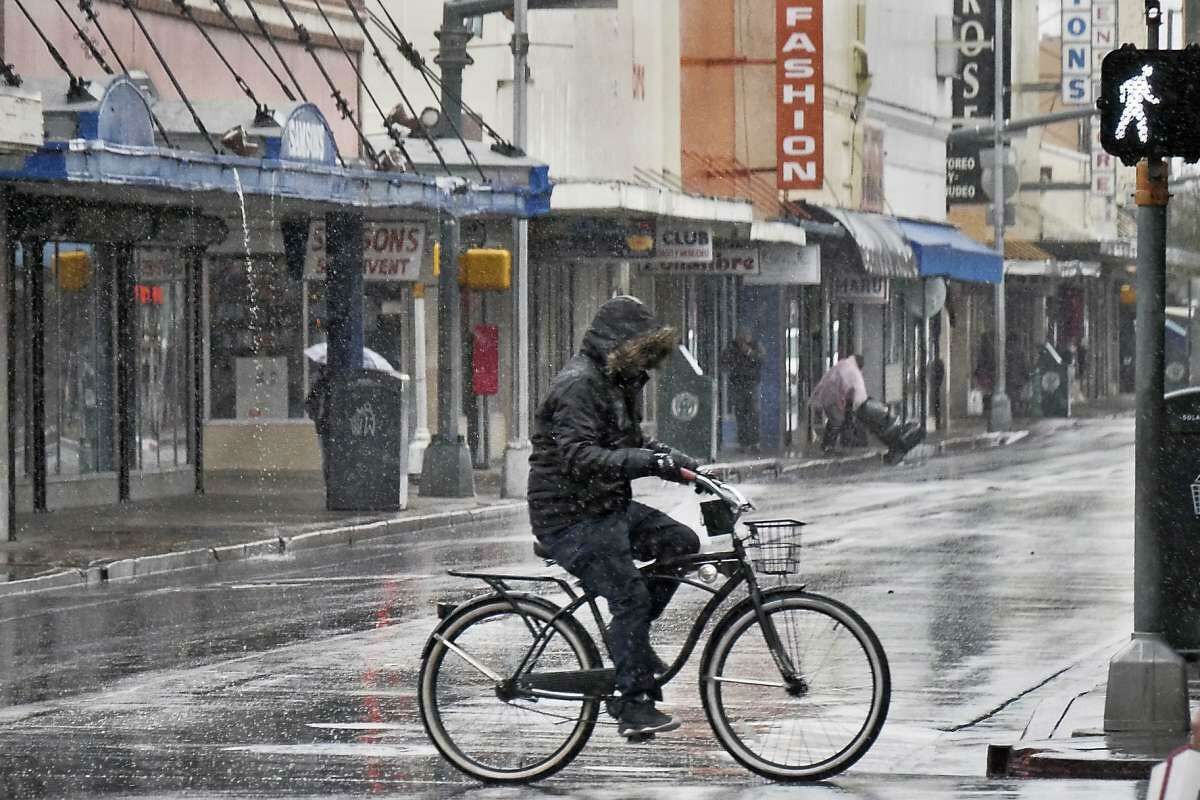 A cyclist braves the cold temperatures, rain and ice pellets that fell in the area as he rides his bicycle on Hidalgo Street in downtown Laredo, Thursday, Dec. 7, 2017.