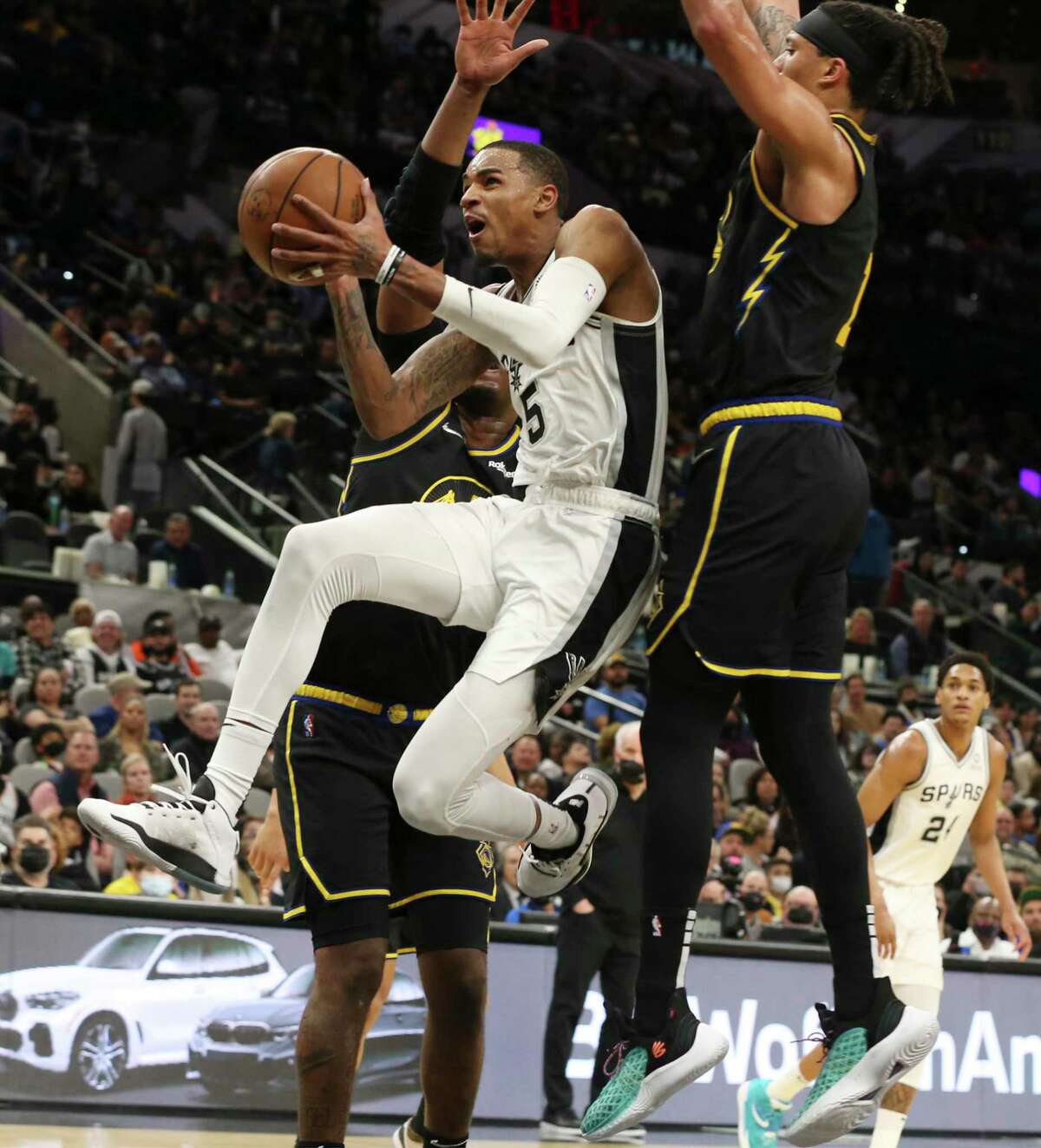 Spurs’ Dejounte Murray (5) splits a pair of Golden State Warriors for a score during the first half of the game at the AT&T Center on Tuesday, Feb. 1, 2022.