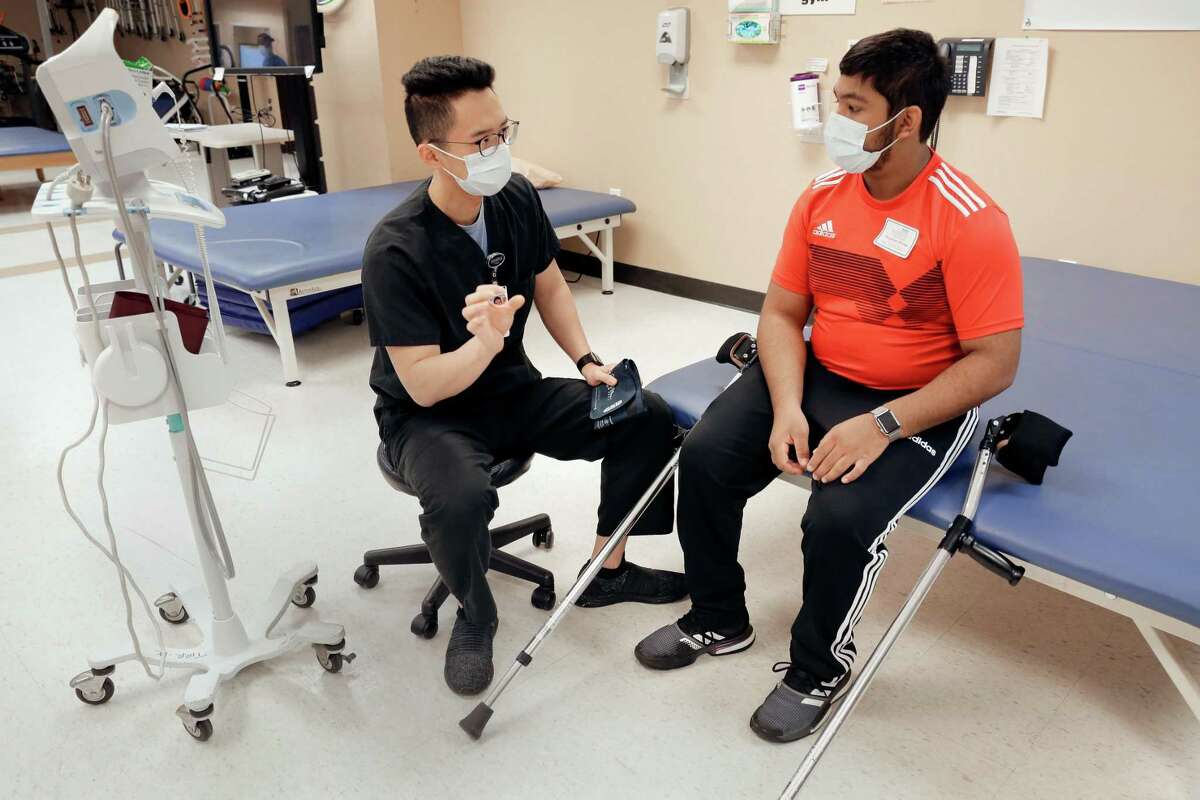 Patient Himanshu Prasad, right, consults with during a physical therapist Jeffrey Wu, left, before beginning the training regimen at TIRR Memorial Hermann Monday, Dec. 13, 2021 in Houston, TX. Prasad had surgery to treat a form of cerebral palsy/spasticity he had since birth, allowing him to increase his mobility beyond wheel chairs and crutches.