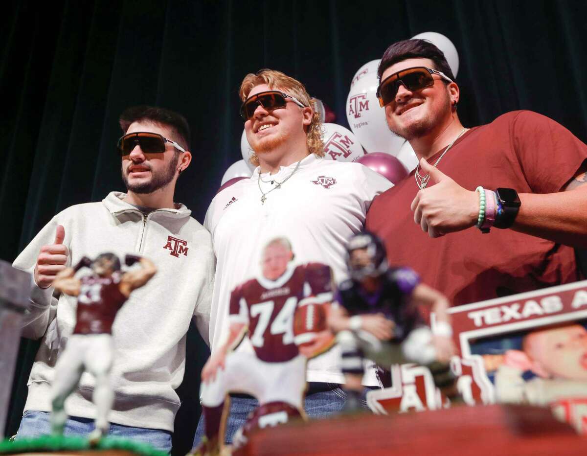 Zach Rogers, center, poses for photos with teammates after signing to play football for Texas A&M during a National Signing Day ceremony at Willis High School, Wednesday, Feb. 2, 2022, in Willis.