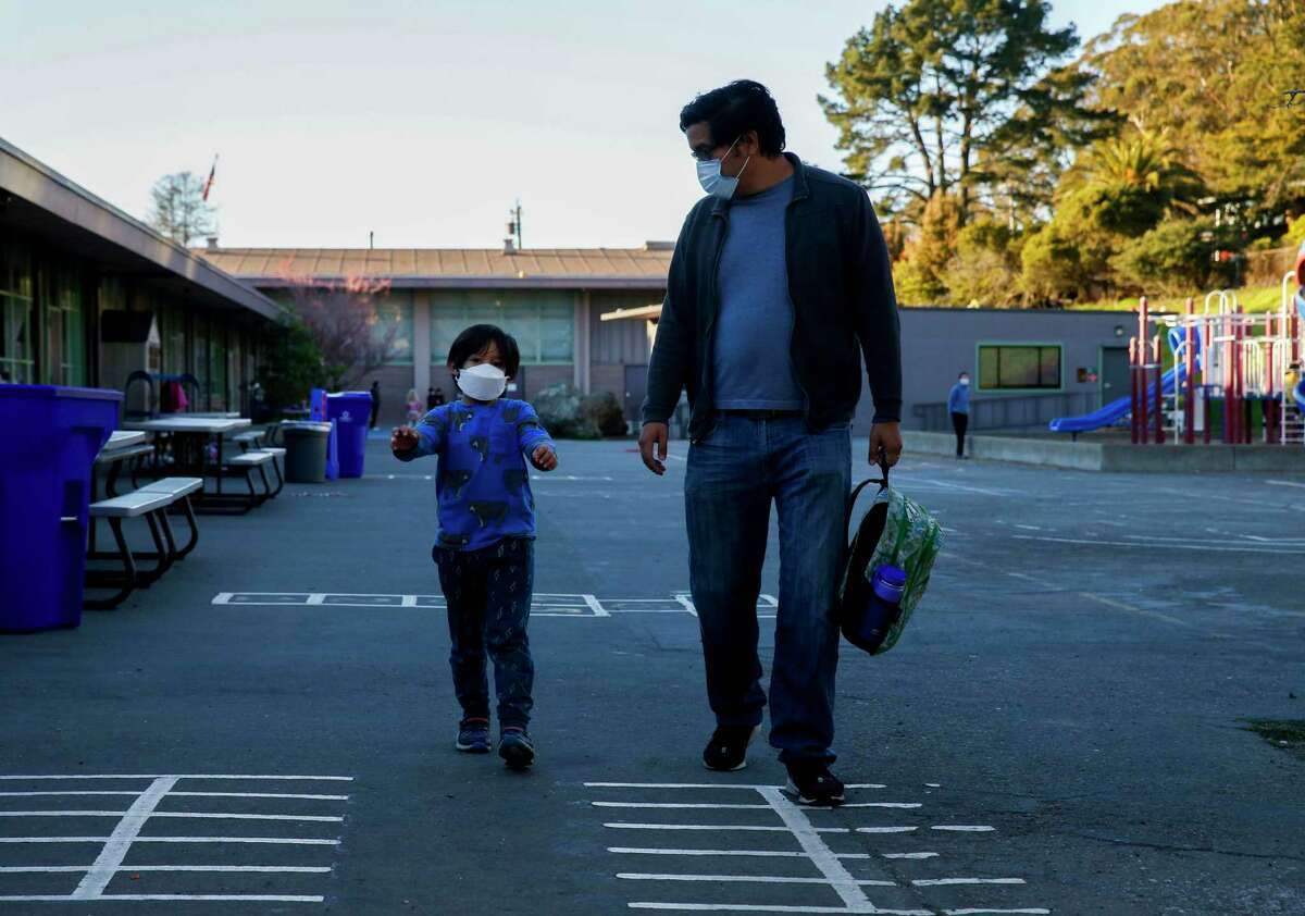 Ernesto Falcon picks up his son, Gabriel from Madera Elementary on Tuesday, Feb. 1, 2022, in El Cerrito , Calif. Falcon allows his son to take off his mask once he’s outside his afterschool program as he would like to see masking outside no longer required for kids at school.