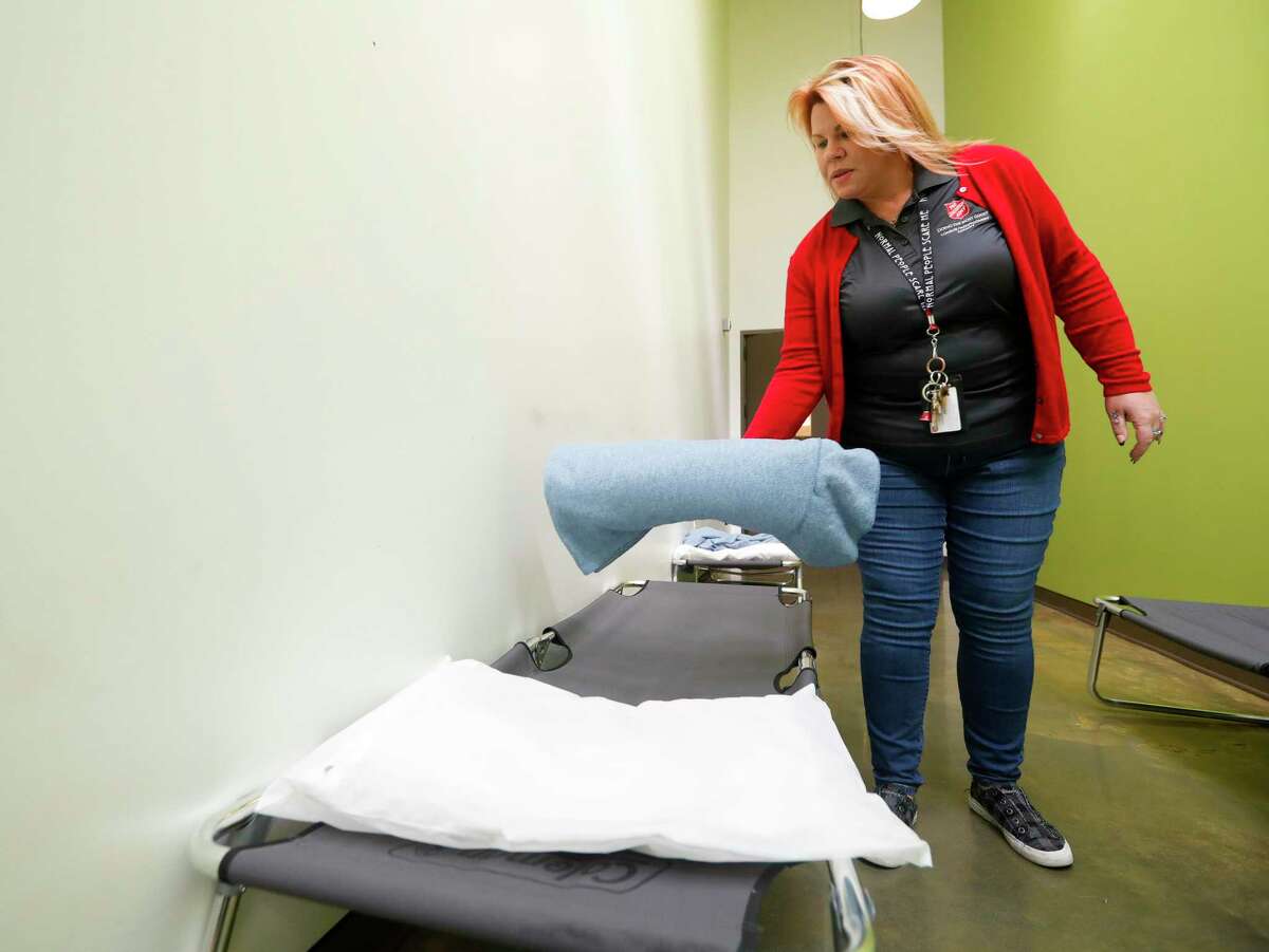Shelter director Bonnie Atzenhoffer puts out blankets on foldable cots as she prepares for an increase in guest traffic at the Salvation Army Wayne Bergstrom Center of Hope, Friday, Jan. 28, 2022, in Conroe.