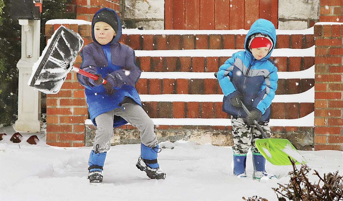 John Badman|The Telegraph Oliver Burton, 6, left, and his brother, Theodore, 4, were helping to clear the snow from the sidewalk in front of their home in the 2200 block of Brown Street in Alton Wednesday morning.