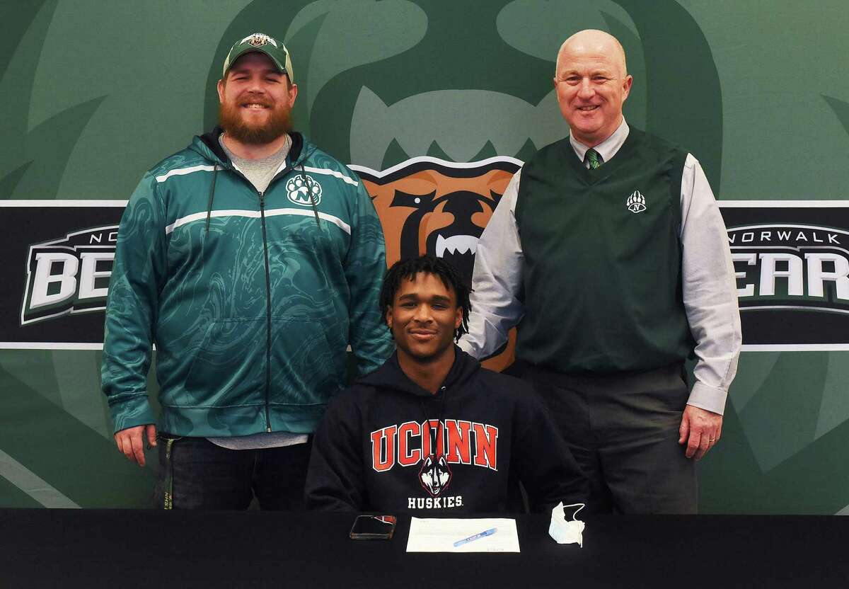 Norwalk’s Cam Edwards with football coach Pat Miller, left, and athletic director Doug Marchetti during a ceremony for Edwards, who signed his National Letter of Intent to play for UConn on Wednesday at Norwalk High.
