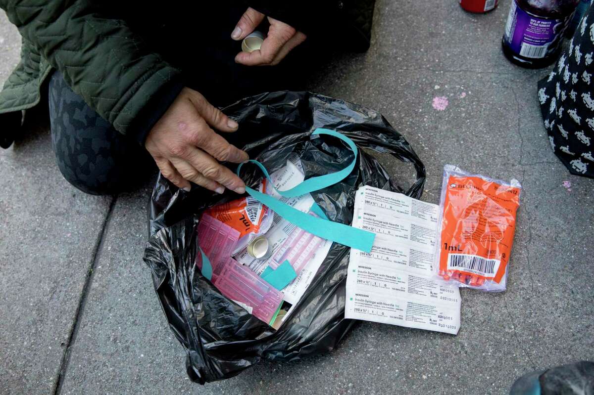 A homeless woman sifts through her bag of fentanyl-smoking paraphernalia along Turk Street in San Francisco in 2020.