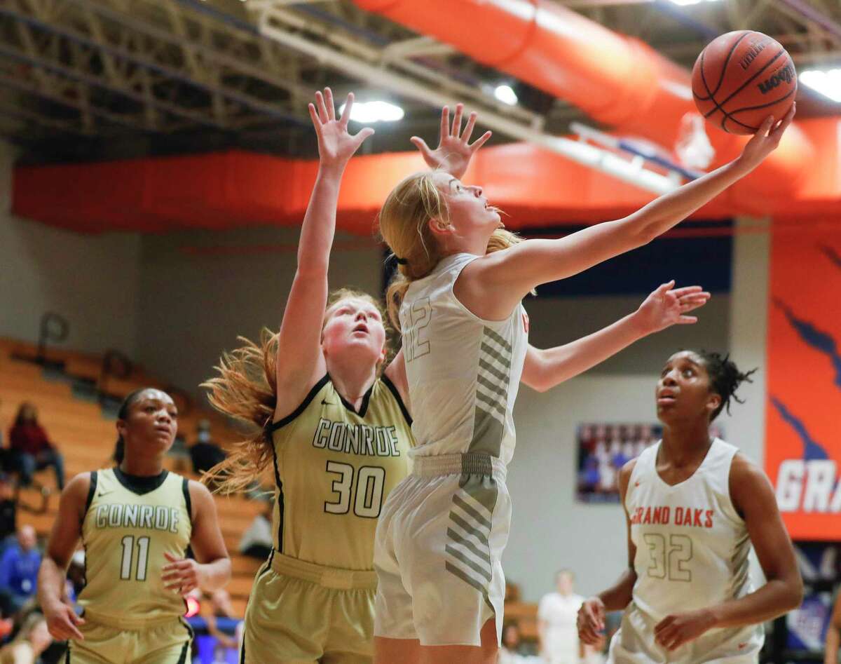 Grand Oaks' Kylee Myers (12) shoots under the basket against Conroe's Makenzie Castille (30) during the first quarter of a high school basketball game at Grand Oaks High School, Wednesday, Feb. 2, 2022.
