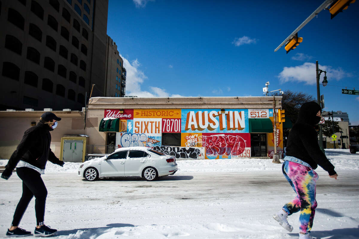 AUSTIN, TX - FEBRUARY 15: Pedestrians walk on along a snow-covered street on February 15, 2021 in Austin, Texas. Winter storm Uri has brought historic cold weather to Texas, causing traffic delays and power outages, and storms have swept across 26 states with a mix of freezing temperatures and precipitation. (Photo by Montinique Monroe/Getty Images)
