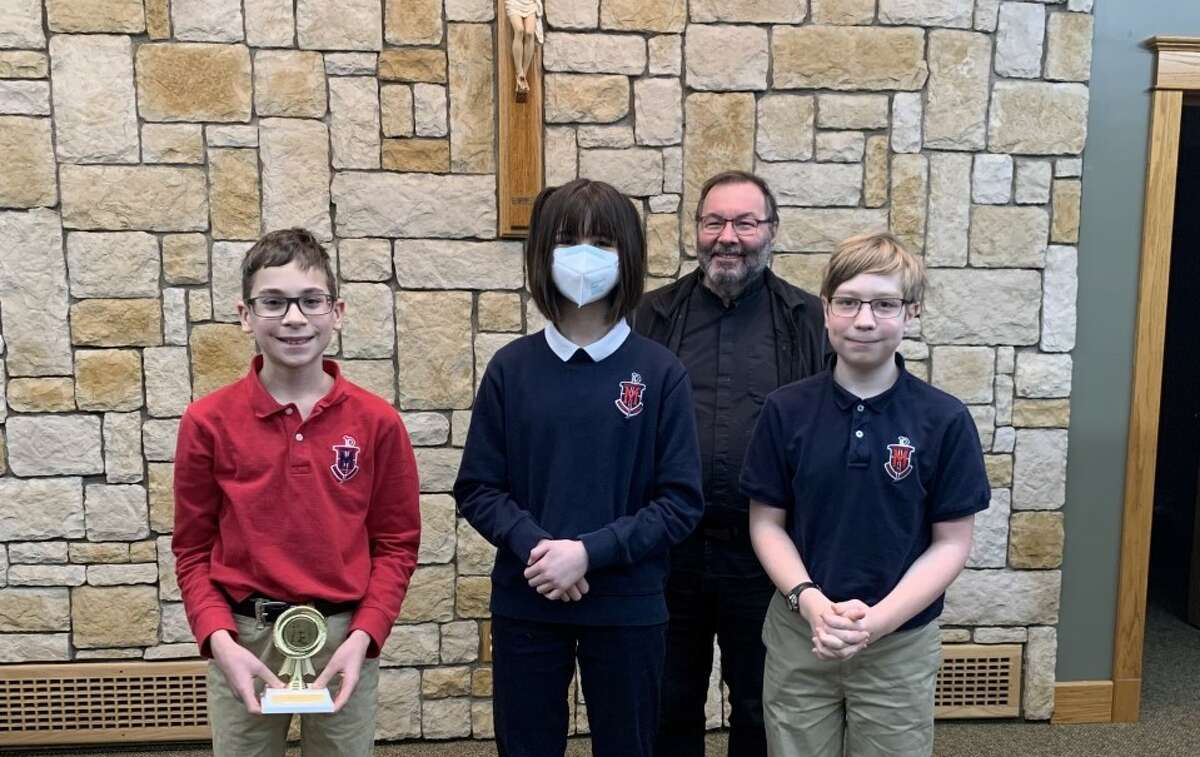 The top three finishers in Manistee Catholic Central's catechism bee, Easton Kequom, Trinity Hurford and  Cory Whitman pose for a photo in front of Father Zeljko. As the winner, Kequom moves on to compete  in the 11th Annual Diocesan Regional Catholic Schools Catechism Bee in Gaylord this spring.