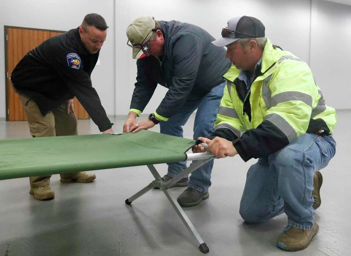 Workers with the Montgomery County Precinct 1 Commissioner’s office set up a cot in the Lone Star Community Center as temperatures plunge toward freezing, Thursday, Feb. 3, 2022, in Montgomery. The 320 person capacity center opens as a warming center for those who need shelter at 6:00 p.m.