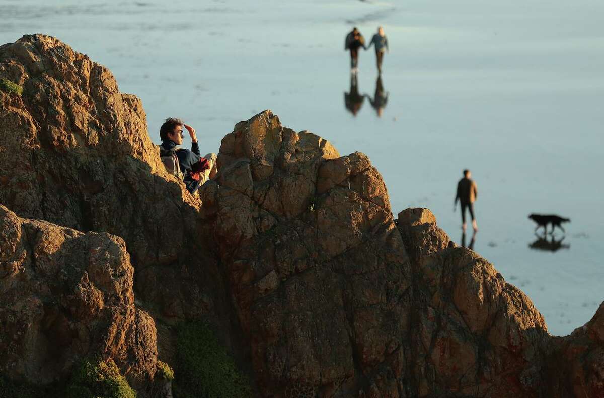 一名男子在旧金山兰兹角的一块露出地面的岩石上观看日落。2014- 2016年，海洋热浪袭击了加州海域。