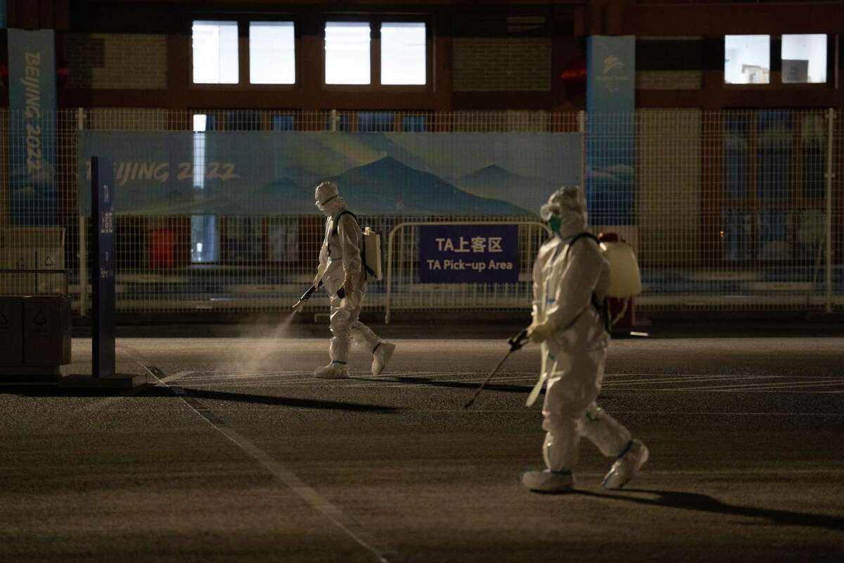 Workers wearing full personal protective kit spray disinfectant at Banqan Service Area on February 2, 2022 in Yanqing, China.