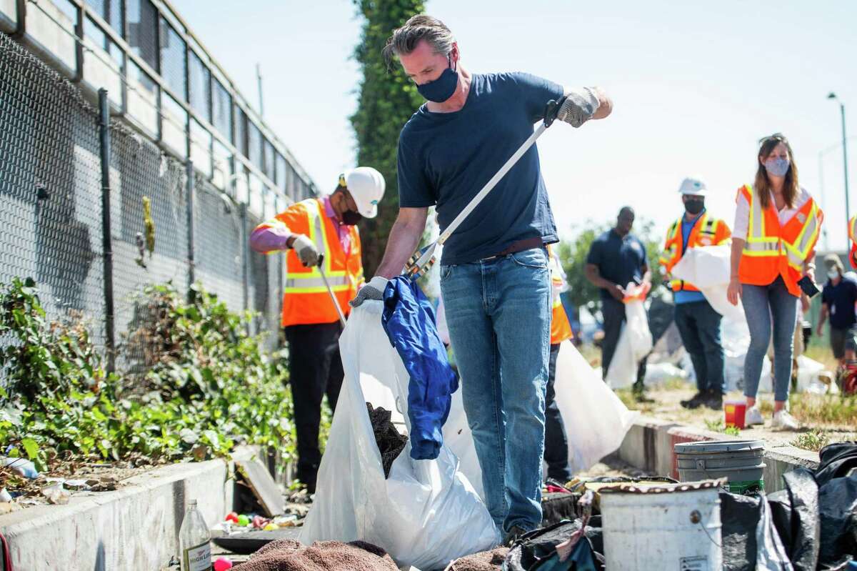 Gov. Gavin Newsom helps tidy a Los Angeles Caltrans property in May. He also has to clean up legislative messes at the Capitol.