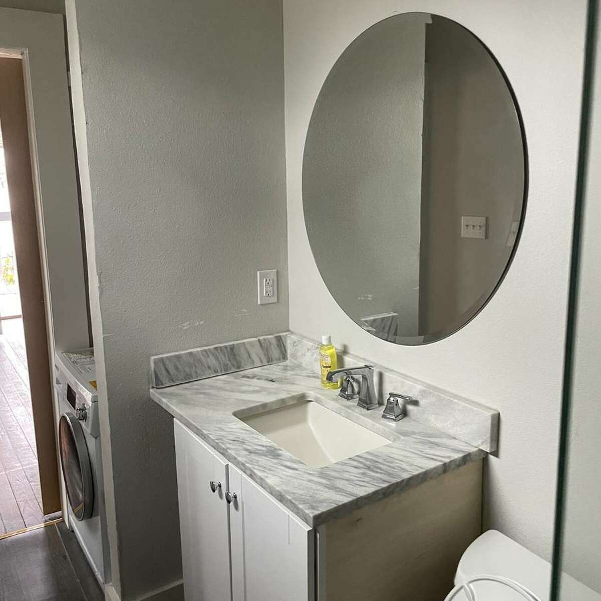 the sliding barn door leads to the bathroom with a nook for a washer and dryer