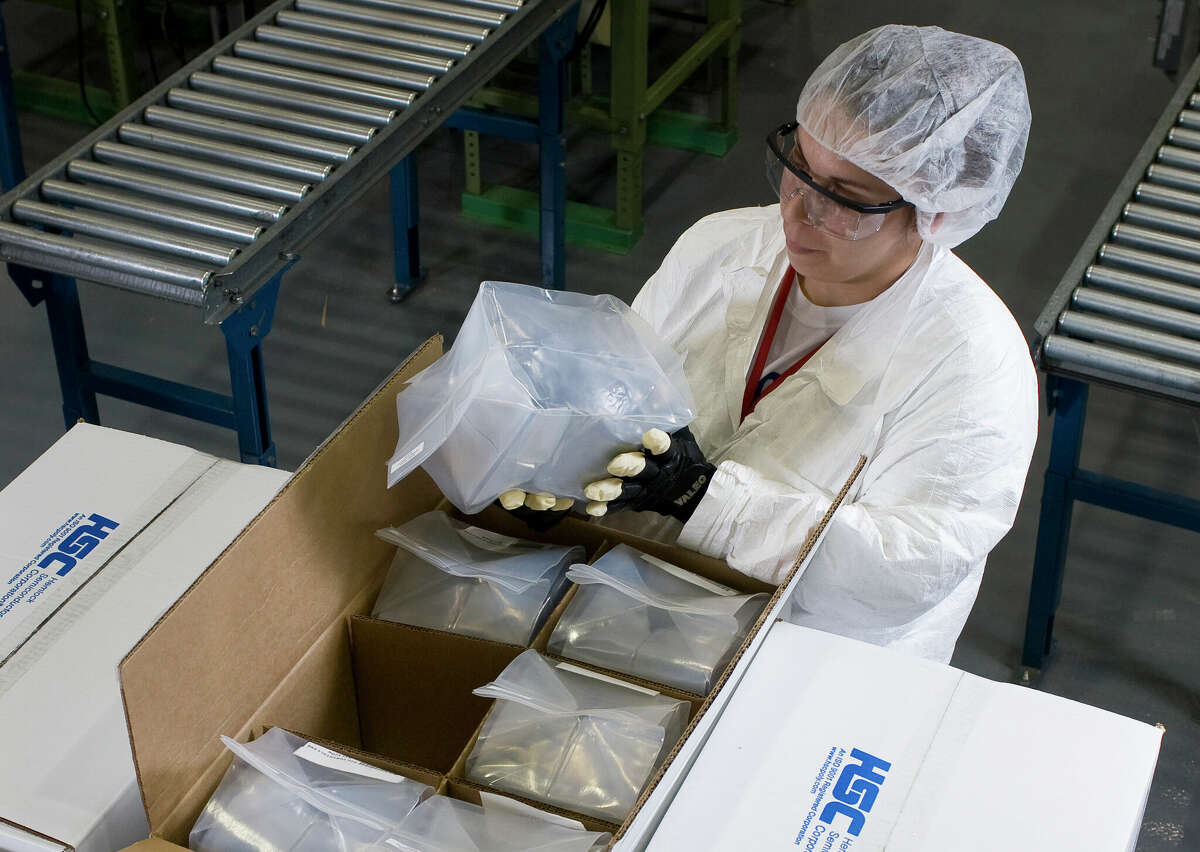 FILE - A worker at Hemlock Semiconductor examines boxes of polysilicon before they’re shipped to customers. Workers wear protective clothing to avoid contaminating the hyper-pure polysilicon that Hemlock produces for the semiconductor and solar industries.