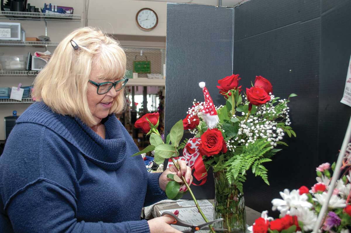 JoAnn Chumley, owner of All Occasions Flowers and Gifts in Jacksonville, prepares a bouquet of roses Friday at her downtown shop. Valentine's Day spending is expected to climb again this year. 