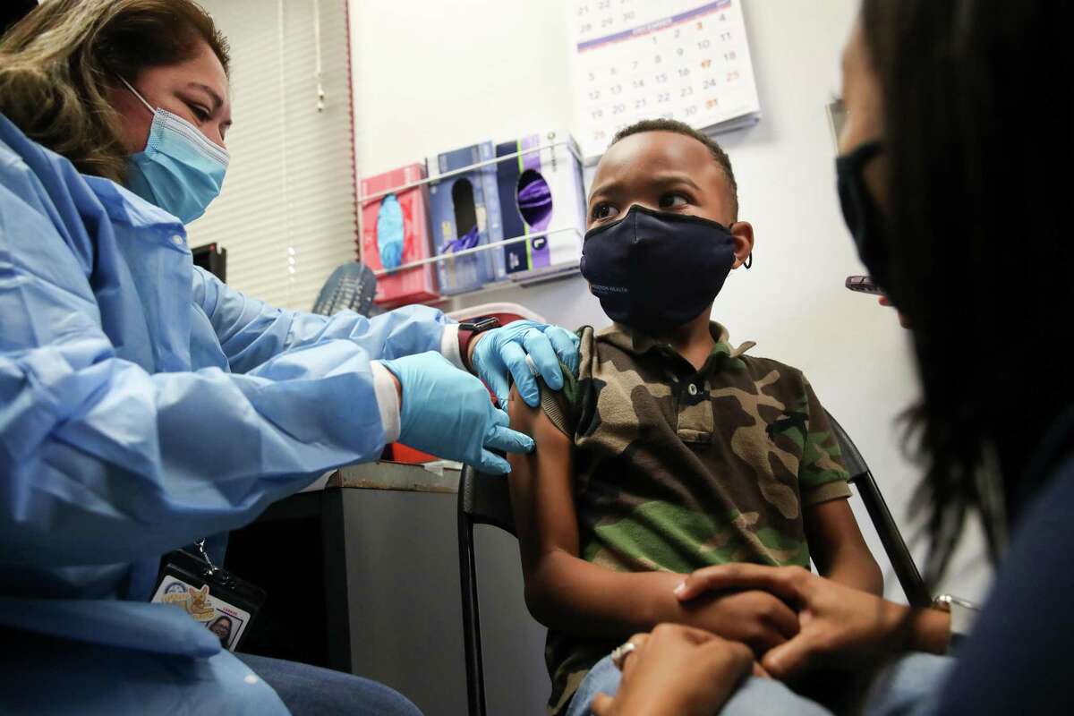 Claude Ruth, III, 6, holds his mother’s hand as he gets a Pfizer pediatric COVID-19 vaccine from Isabell Martinez, an LVN, on Friday, Nov. 5, 2021, at La Nueva Casa de Amigos Health Center in Houston. The shots were among the first to be given out by the city health department around the city that morning.
