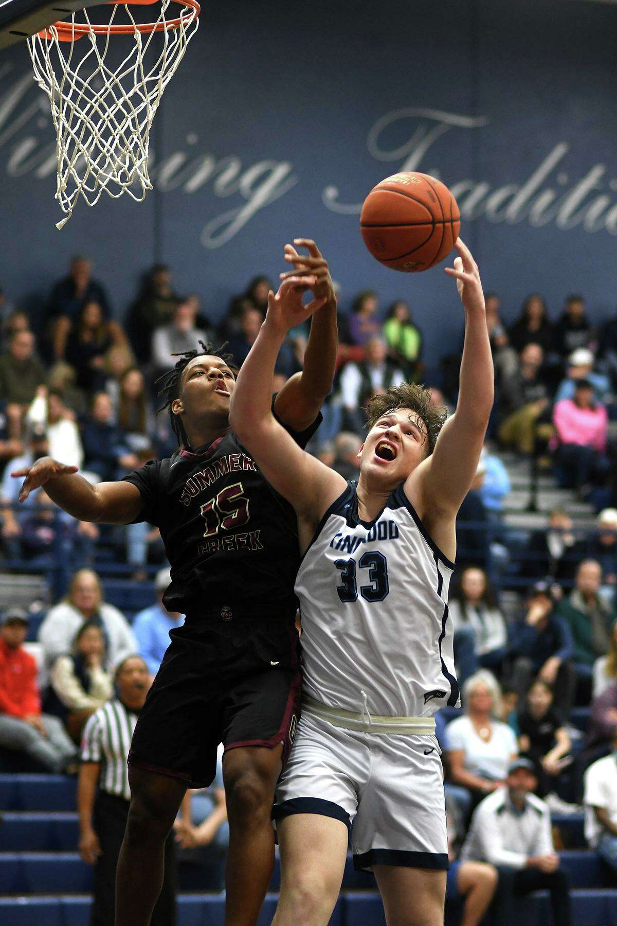 Kingwood senior Mason Carlos (33) gets his shot blocked by Summer Creek junior Cory Nichols (15) during the first quarter of their District 21-6A matchup at Kingwood High School on Friday, Jan. 14, 2022.