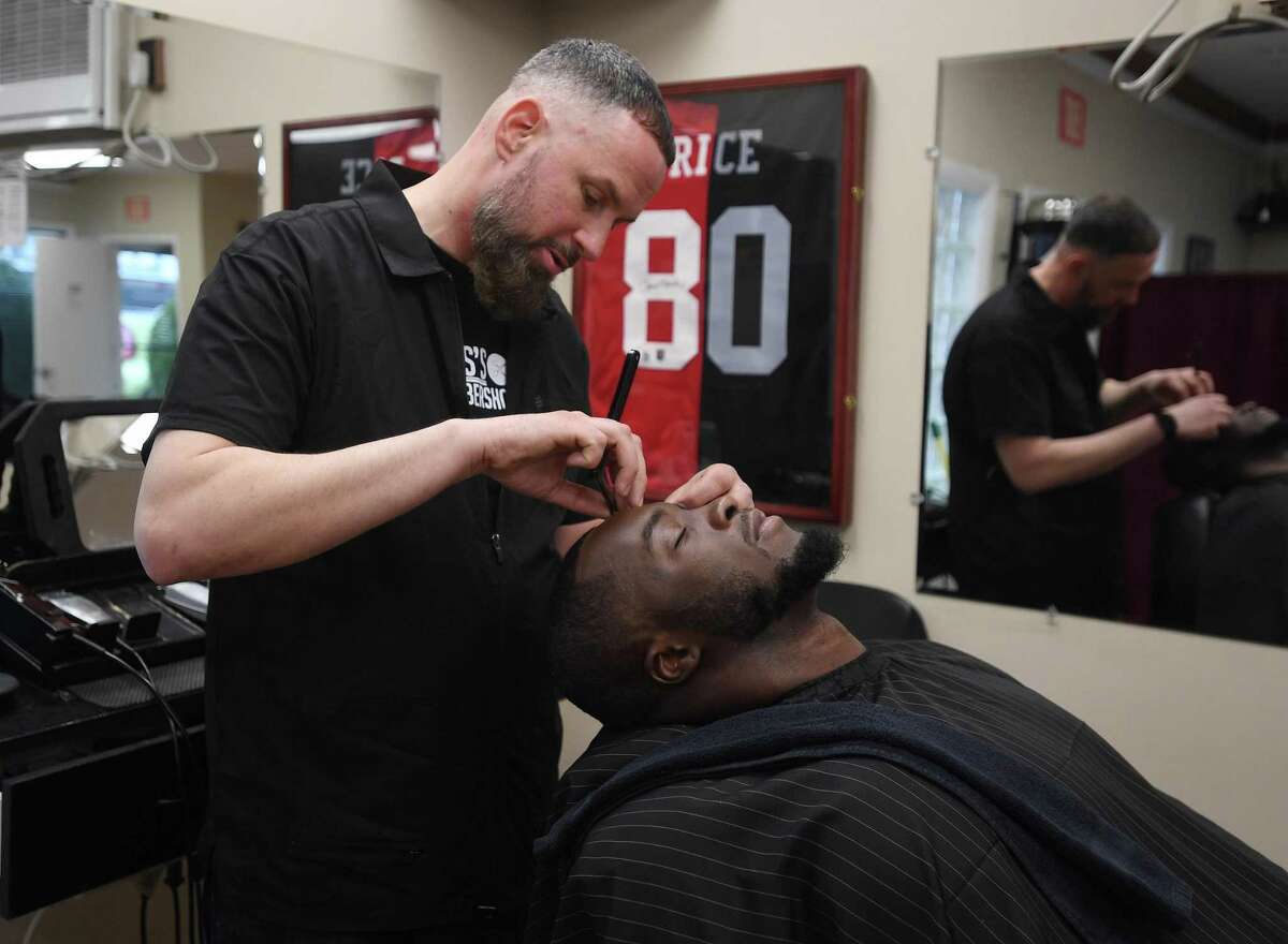 Gus Mandrozos cuts the hair of long time client and former NFL linebacker Kevin Pierre-Louis at his Gus' Barbershop, celebrating 10 years in business at 58 Van Zant Street in Norwalk, Conn. on Thursday, February 3, 2022. Pierre-Louis, who plays for the Houston Texans, is a Norwalk native.