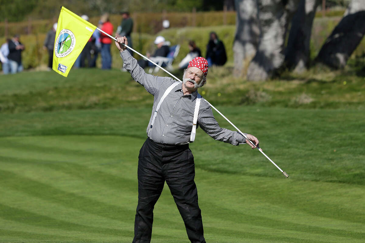 Actor Bill Murray stretches with the flag on the fifth green at Pebble Beach Golf Links during the third round of the AT&T Pebble Beach Pro-Am golf tournament on Saturday Feb. 9, 2013 in Pebble Beach, Calif. (AP Photo/Eric Risberg )