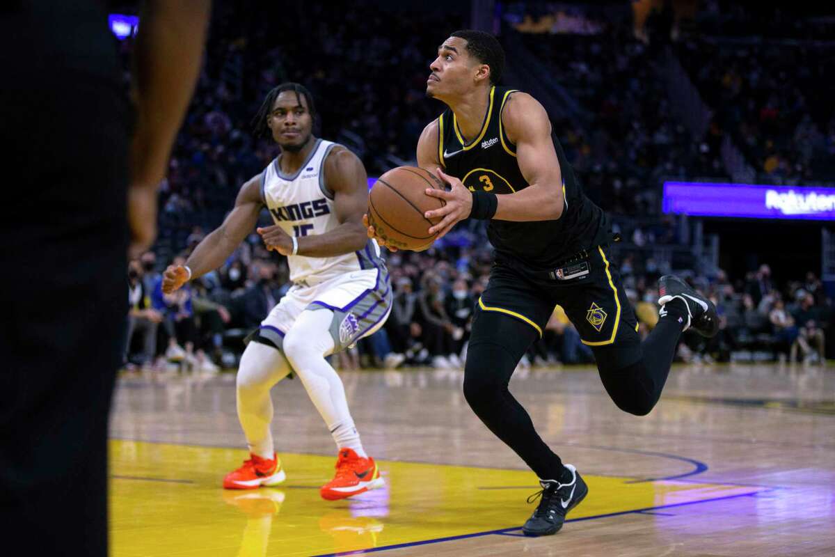 Golden State Warriors guard Jordan Poole (3) loses his footing as he drives to the basket past Sacramento Kings guard Davion Mitchell (15) during the fourth quarter of an NBA basketball game Thursday, Feb. 3, 2022, in San Francisco. The Warriors won 126-114. (AP Photo/D. Ross Cameron)