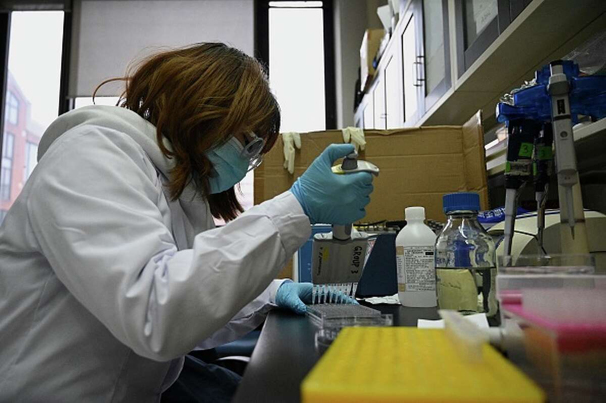 A technician works with monoclonal antibody treatment in a lab.
