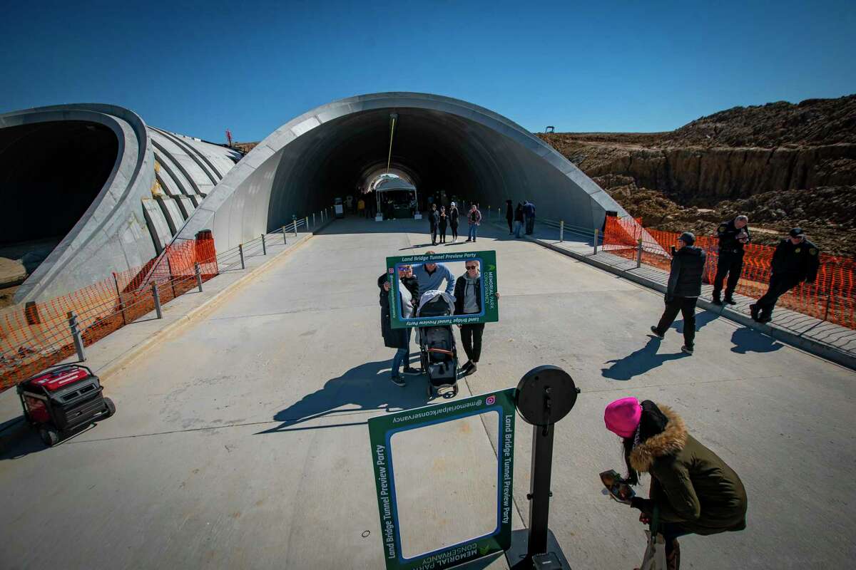 People take pictures as they walk through one of the tunnels that will contain Memorial Drive and allow a land bridge to cross the thoroughfare, connecting both sides of Memorial Park, Saturday, Feb. 5, 2022, in Houston. The land bridge is part of the park’s 10-year-plan.