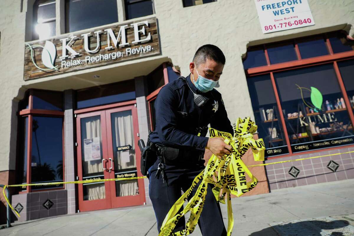 A police officer collects caution tape Tuesday outside the scene of a shooting at Kume spa in Oakland.